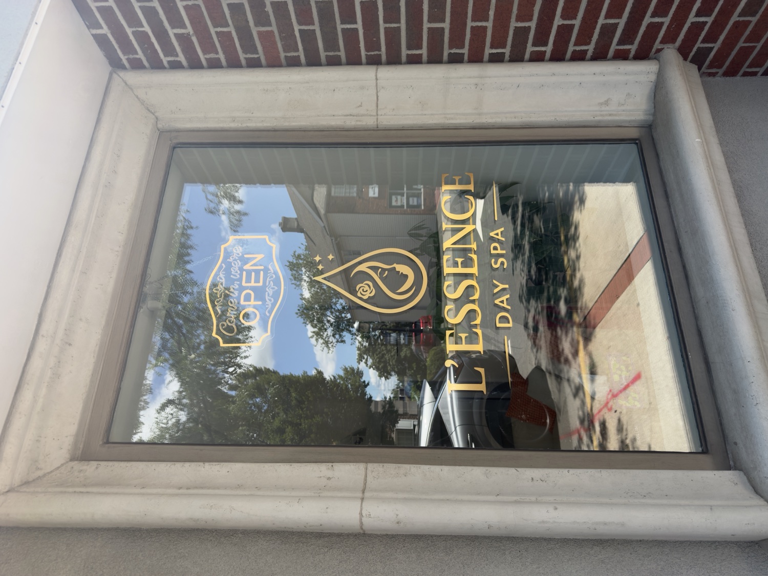 The L'Essence Day Spa storefront window with gold logo on Main Street, Metuchen, NJ